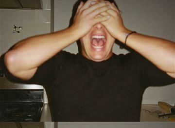 Man covering his face and screaming in a kitchen during a party