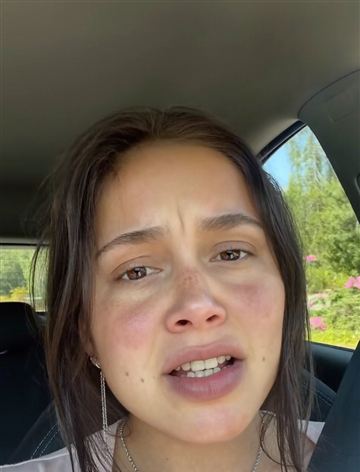 Upset woman talking to the camera from the driver seat of a parked car